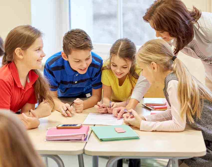 Vier Schülerinnen und Schüler sitzen auf einem Tisch und erarbeiten etwas gemeinsam