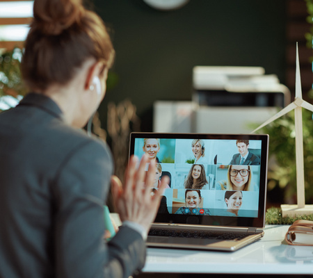 Seen from behind modern female with laptop having video meeting in modern office.
