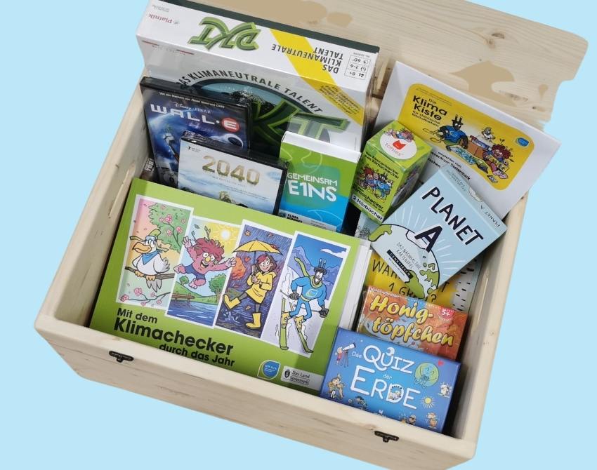 Geöffnete Holzbox mit Büchern, Spielen, Hörbüchern und Filmen als Inhalt.