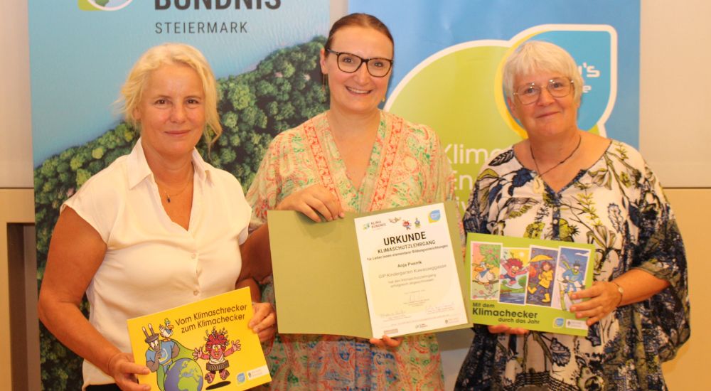 3 Personen vor Roll-ups mit Urkunden und Büchern in der Hand