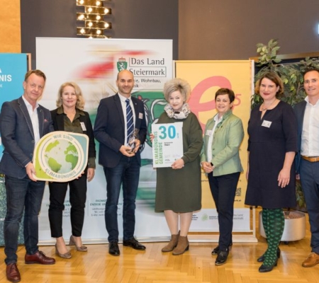 Klimabündnis Auszeichnungsgala: Gemeindevertreter stehen mit Vorständen vor dem Klimabündnis und Land Steiermark Rollup und lächeln. Sie halten die Auszeichnungen in den Händen.