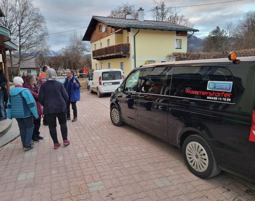 mehrere Menschen stehen draußen vor dem Gebäude und reden
