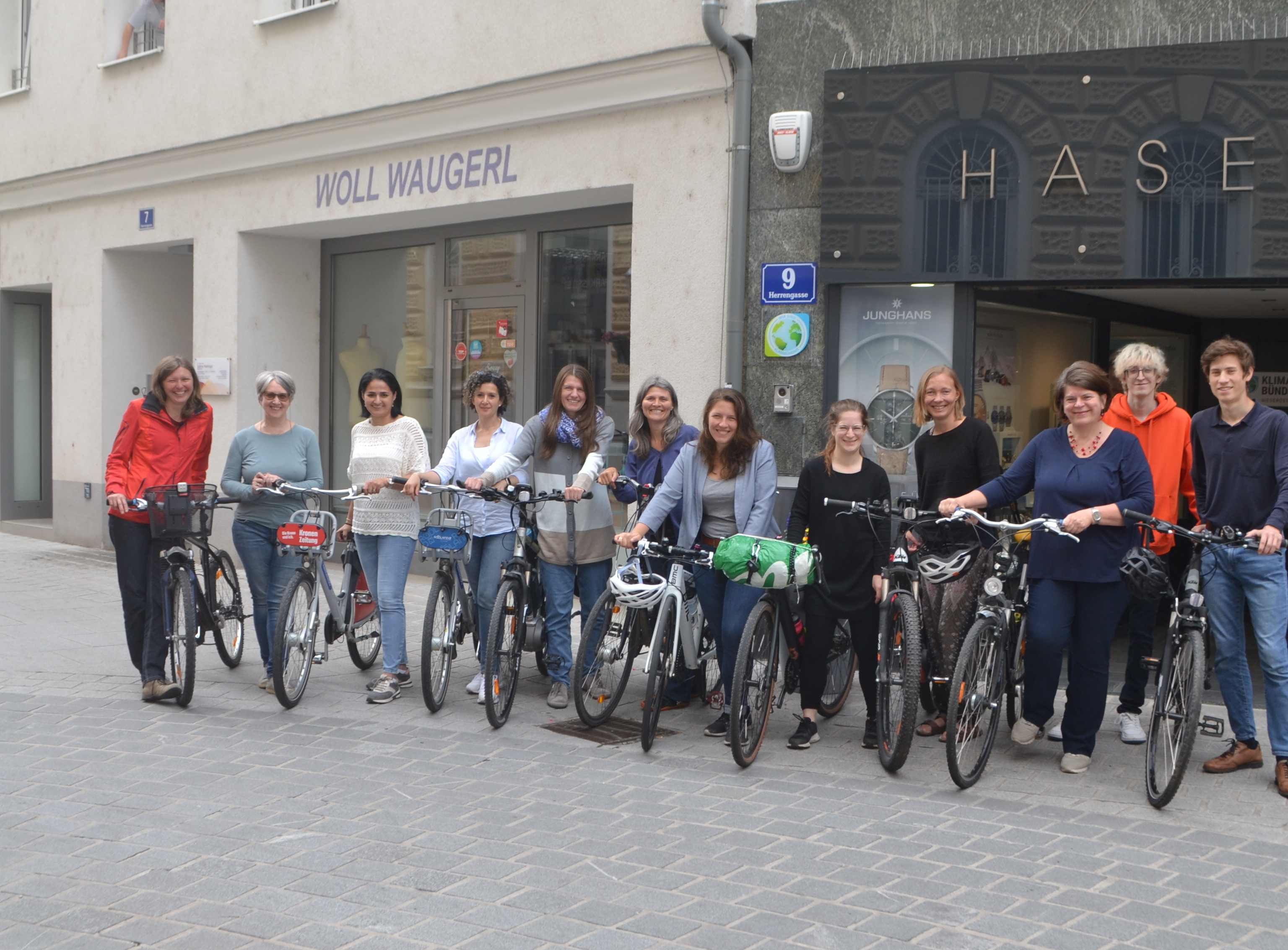 Gruppe von Menschen mit Fahrrädern vor Geschäften in einer Straße