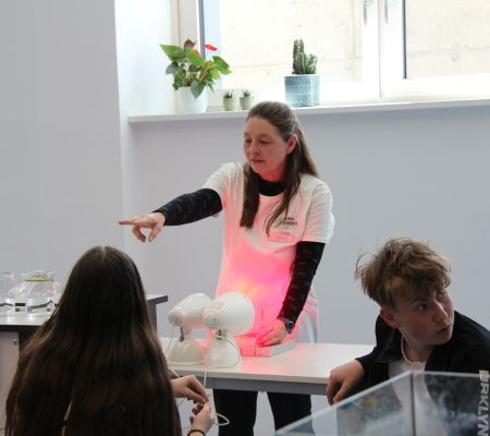 Frau zeigt Experiment mit Wärmelampen