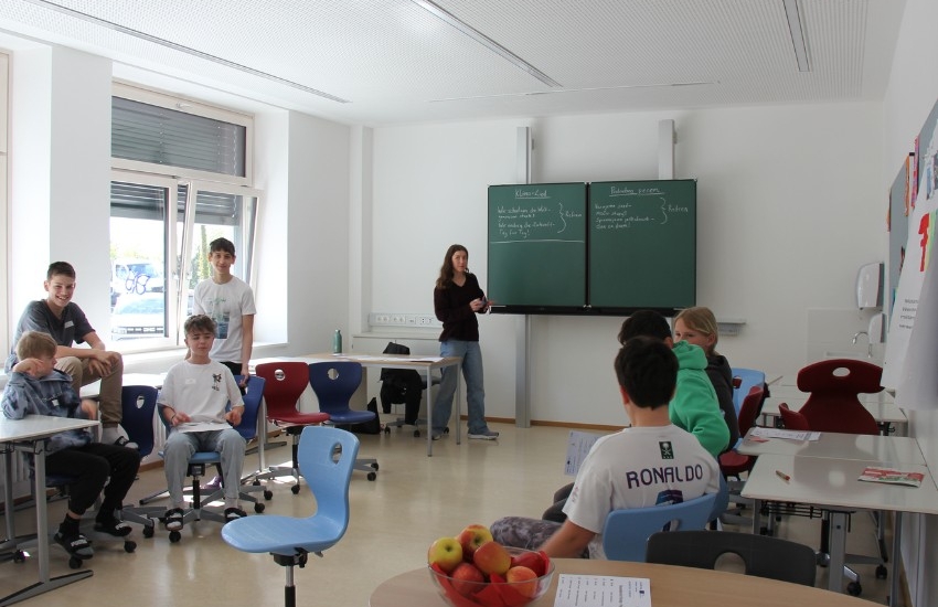 Frau spricht an Tafel vor Schüler:innen