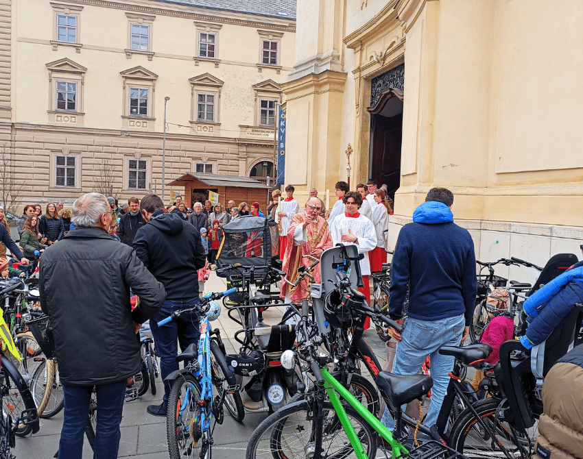 Pfarrer segnet zusammen mit Ministrant die Fahrräder vor der Kirche